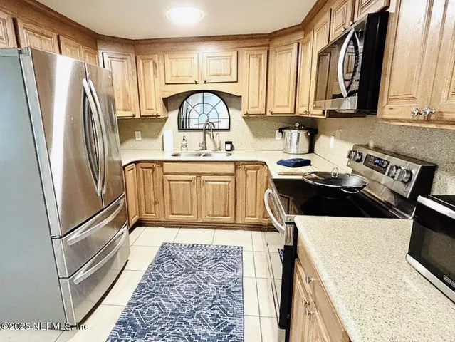 a kitchen with stainless steel appliances granite countertop a refrigerator a stove and a sink with wooden floor