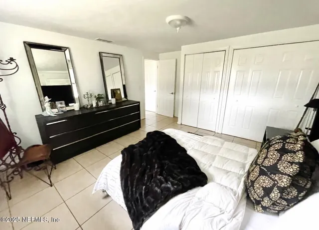 a bedroom with a bed window and mirror