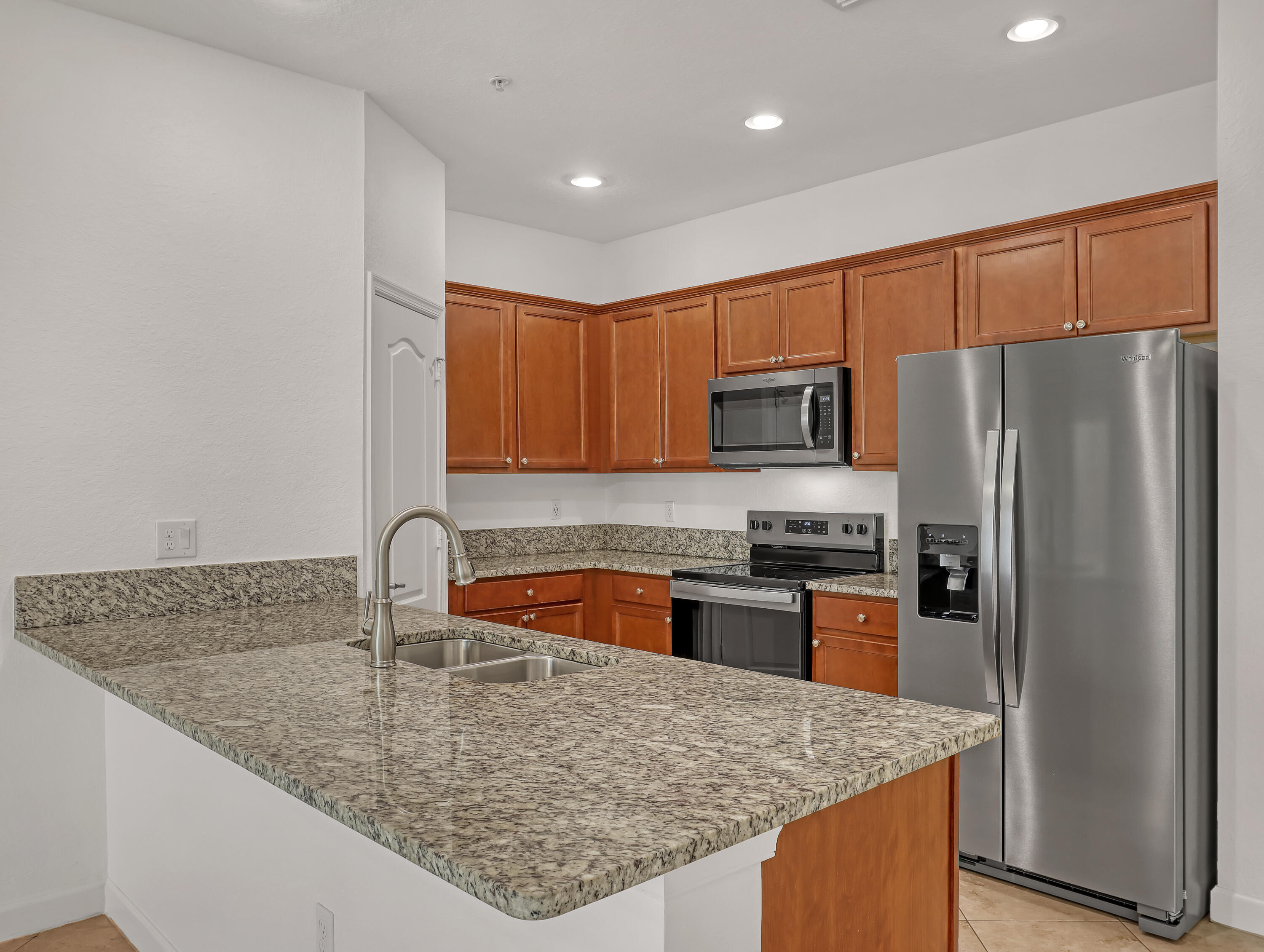 9508 Southwest Otter Lane Stuart, FL 34997 - Photo 12 of 34 a kitchen with granite countertop a sink stove and refrigerator