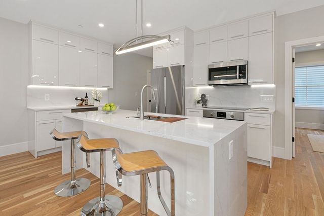 a kitchen with stainless steel appliances a sink a stove a microwave a refrigerator and cabinets