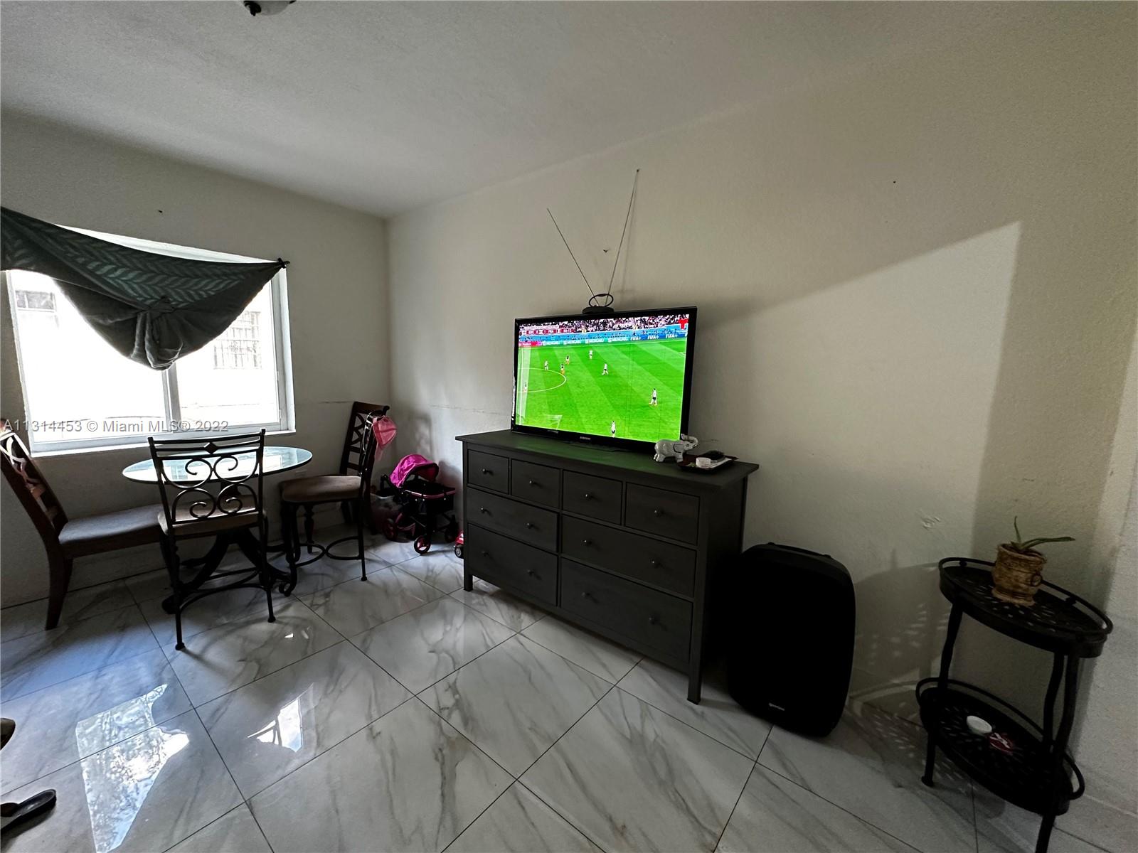 7001 Northwest 6th Avenue Miami, FL 33150 - Photo 3 of 7 a living room with furniture a window and a flat screen tv
