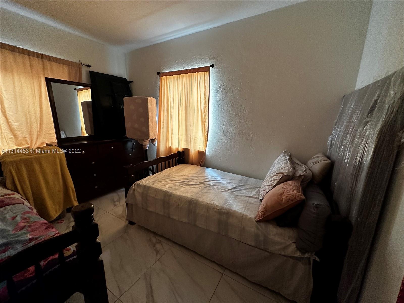 7001 Northwest 6th Avenue Miami, FL 33150 - Photo 6 of 7 a bedroom with a bed television and a window