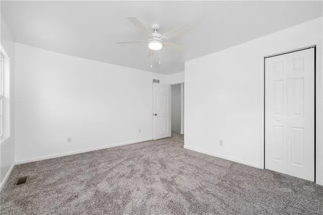an empty room with a ceiling fan and a window
