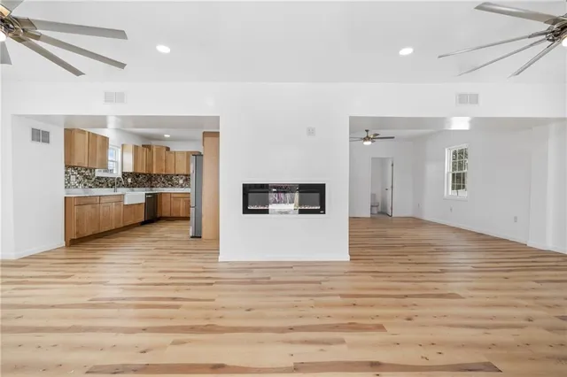 a large white kitchen with wooden floors and stainless steel appliances