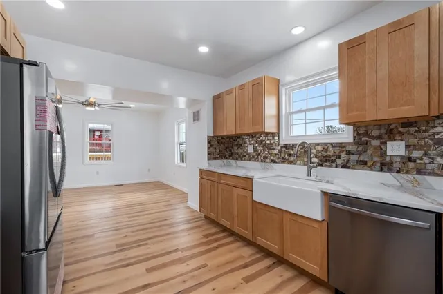 a kitchen with stainless steel appliances granite countertop a sink cabinets and wooden floor