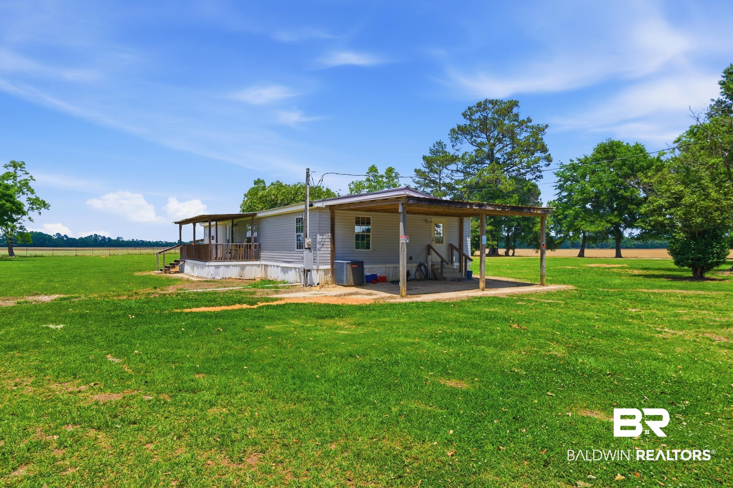 926 Tumbling Lane Atmore, AL 36502 - Photo 41 of 56 Light gray siding exterior with a covered side patio featuring a concrete slab and exposed wood posts