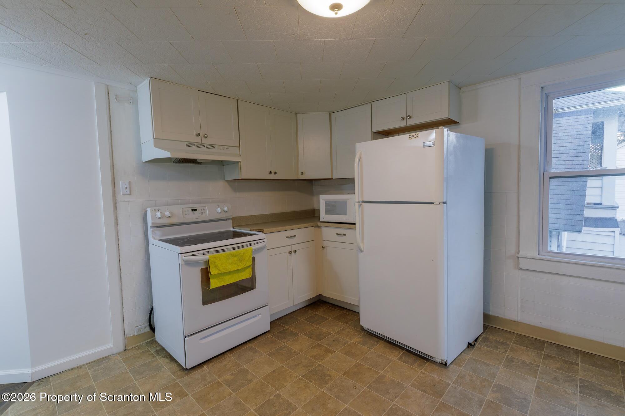 623 East Elm Street, Unit 3 Scranton, PA 18505 - Photo 10 of 18 a kitchen with refrigerator a stove a microwave and a window