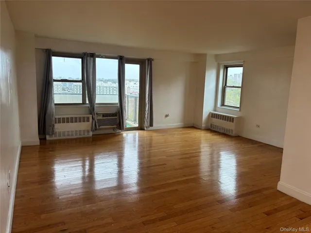 a view of an empty room with window and wooden floor