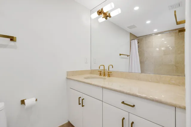 a bathroom with a granite countertop sink a mirror and shower