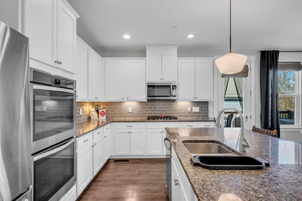 a kitchen with stainless steel appliances granite countertop a sink a stove and a refrigerator