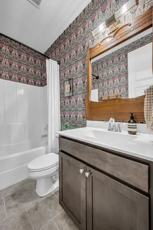 a bathroom with a granite countertop sink a toilet a mirror and shower