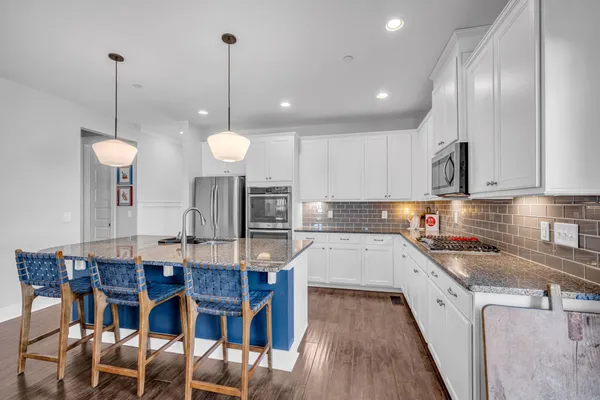 a kitchen with stainless steel appliances granite countertop a sink a stove a refrigerator and island