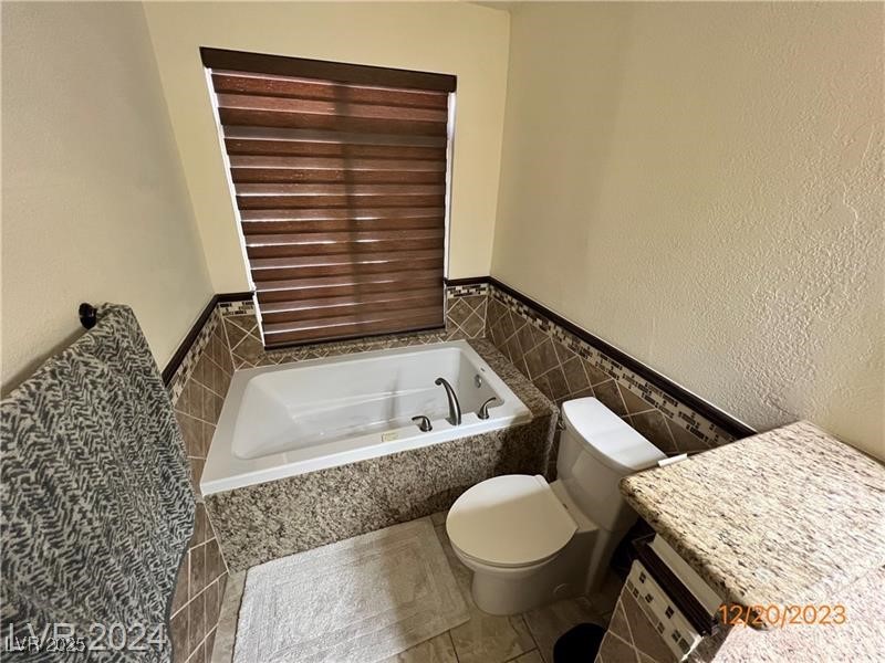 9436 Quail Ridge Drive Las Vegas, NV 89134 - Photo 13 of 17 Bathroom with tile walls, a garden tub, a wainscoted wall, and tile patterned flooring
