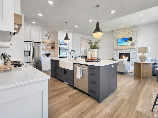 916 Rocky Mountain Way Elk Ridge, UT 84651 - Photo 54 of 54 Dual tone kitchen featuring two tone color scheme, a textured ceiling, open floor plan, stainless steel appliances, and light stone counters
