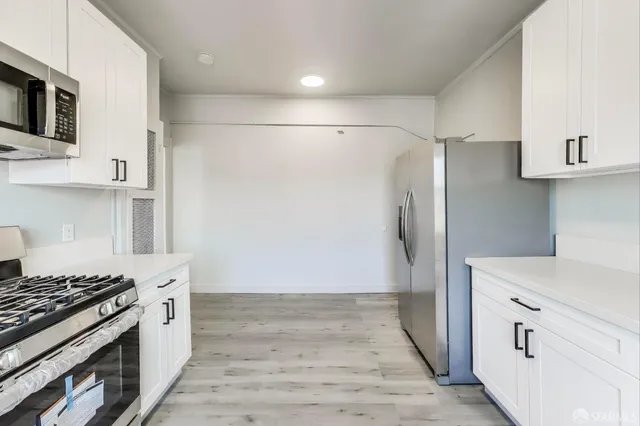 a kitchen with stainless steel appliances white cabinets and wooden floor