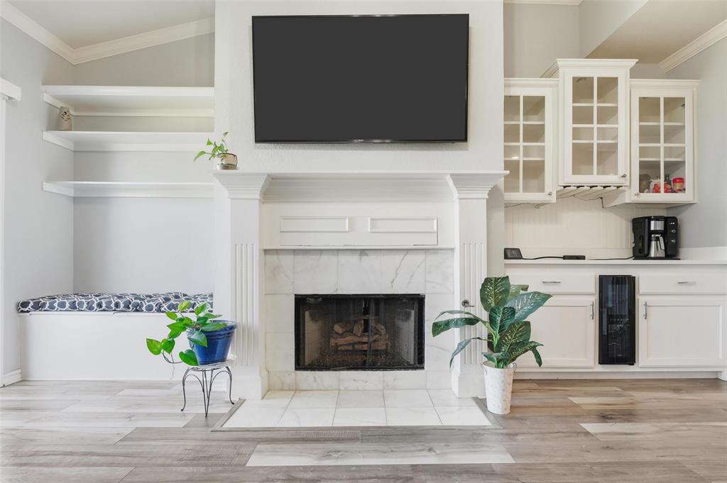 1904 Signal Ridge Place Rockwall, TX 75032 - Photo 8 of 23 Unfurnished living room with ornamental molding, beverage cooler, light wood-style flooring, and a tiled fireplace