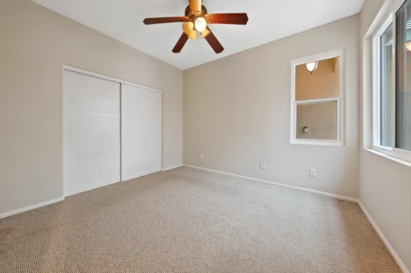 an empty room with chandelier fan and windows