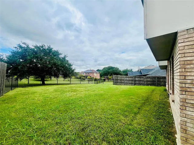 a view of a big yard with a swimming pool and brick wall