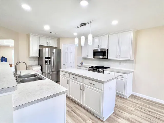 a kitchen with refrigerator stove microwave and sink