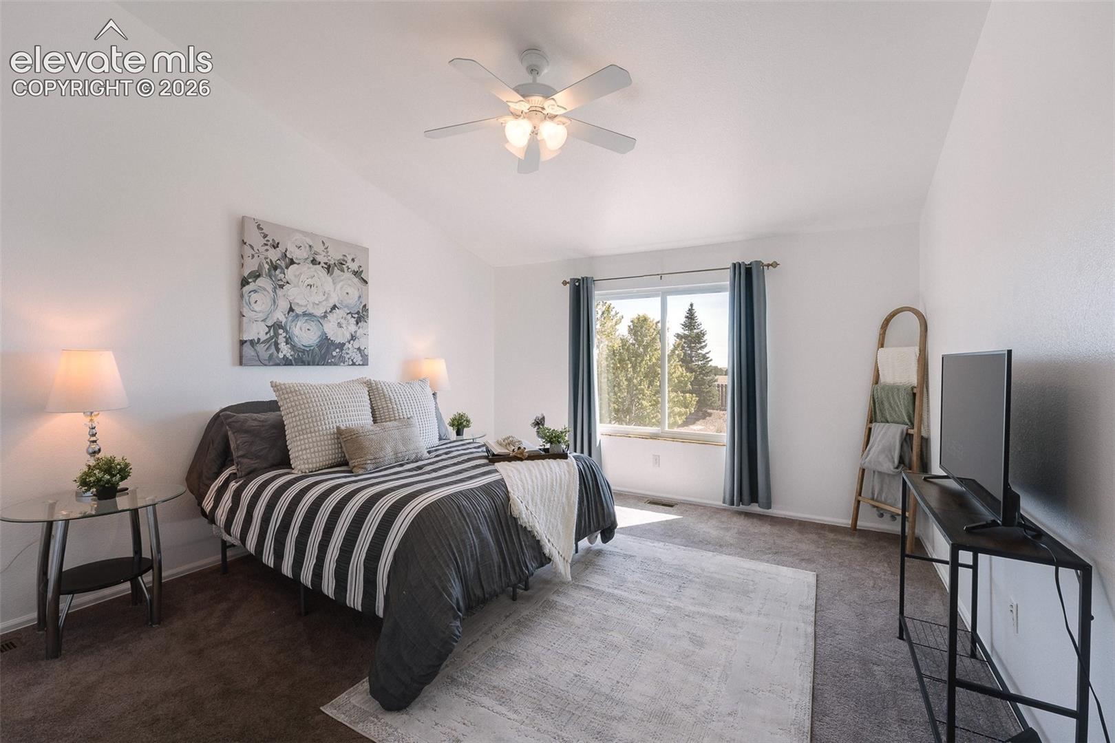 7869 Fort Smith Road Peyton, CO 80831 - Photo 8 of 50 The vaulted Primary Bedroom is a serene retreat with a lighted ceiling fan, neutral carpet, backyard views, a walk in closet, & adjoining 5-piece bathroom.