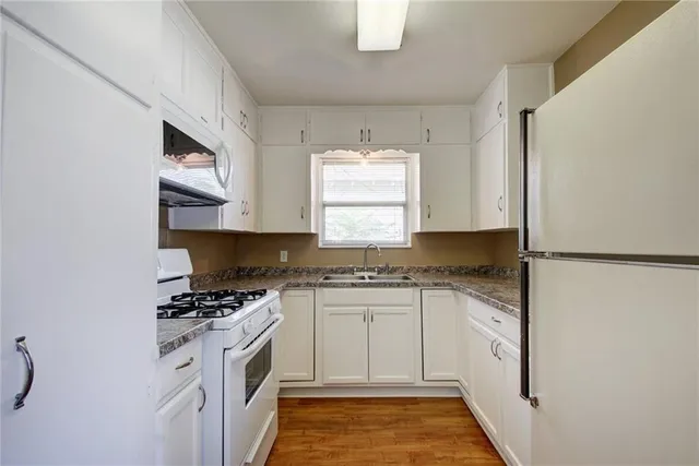 a kitchen with granite countertop a sink stove and cabinets