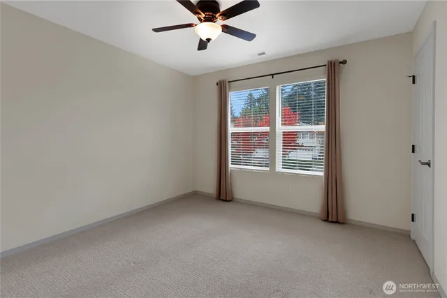 an empty room with ceiling fan and window