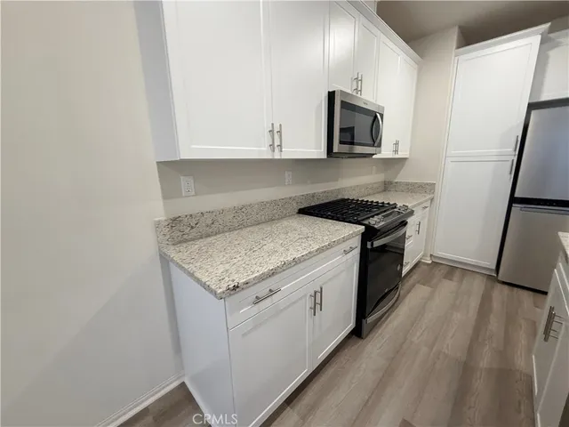 a kitchen with granite countertop cabinets stainless steel appliances and wooden floor