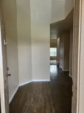 a view of a hallway with wooden floor and a flat screen tv