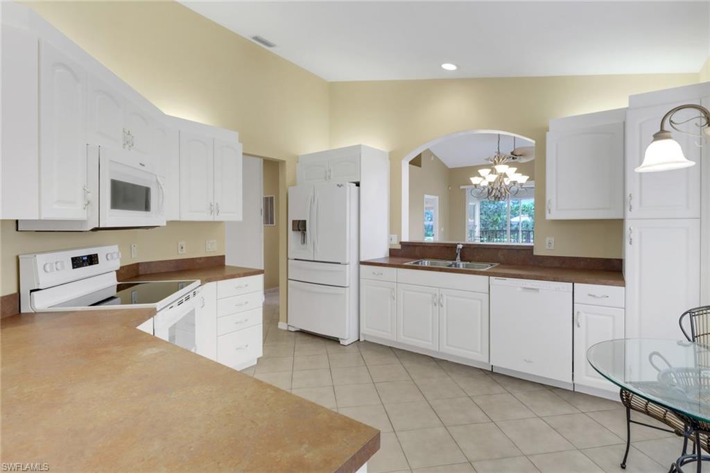 20141 Seagrove Street, Unit 308 Estero, FL 33928 - Photo 14 of 36 a large kitchen with granite countertop a sink white cabinets and stainless steel appliances