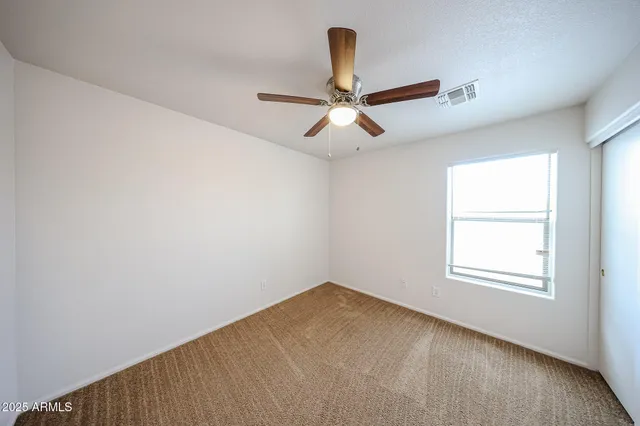 an empty room with a window and a fan