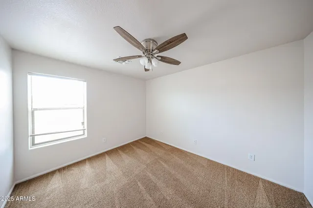 an empty room with a window and a fan
