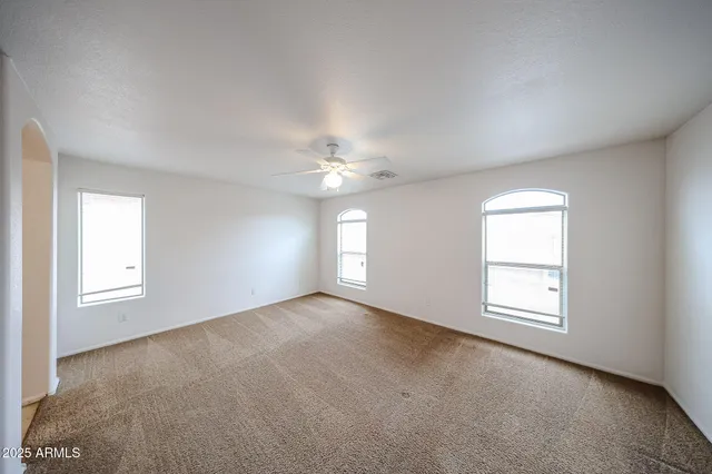 an empty room with windows and ceiling fan