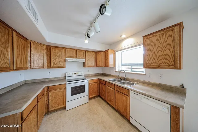 a kitchen with stainless steel appliances granite countertop a sink dishwasher stove and refrigerator