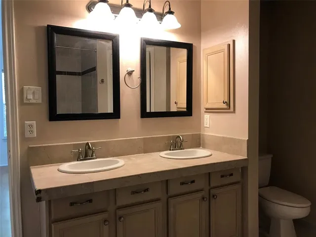 a bathroom with a granite countertop sink a toilet and mirror