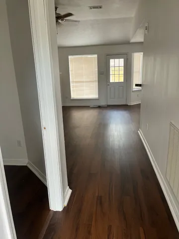 an empty room with wooden floor fire place and windows