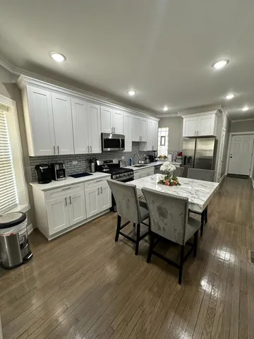 a kitchen with a sink dishwasher a stove a microwave oven and a dining table with wooden floor