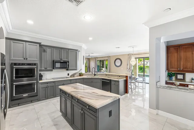a kitchen with stainless steel appliances kitchen island granite countertop a sink refrigerator and cabinets
