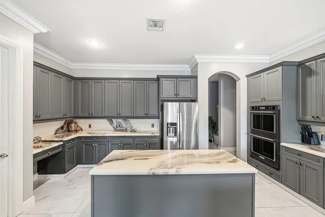 a kitchen with stainless steel appliances kitchen island granite countertop a refrigerator and a sink