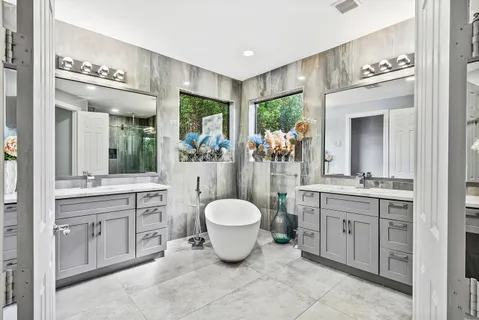 a spacious bathroom with a bathtub a sink and a large mirror