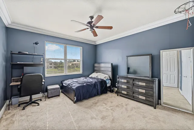 a bedroom with a bed a desk and chair with window