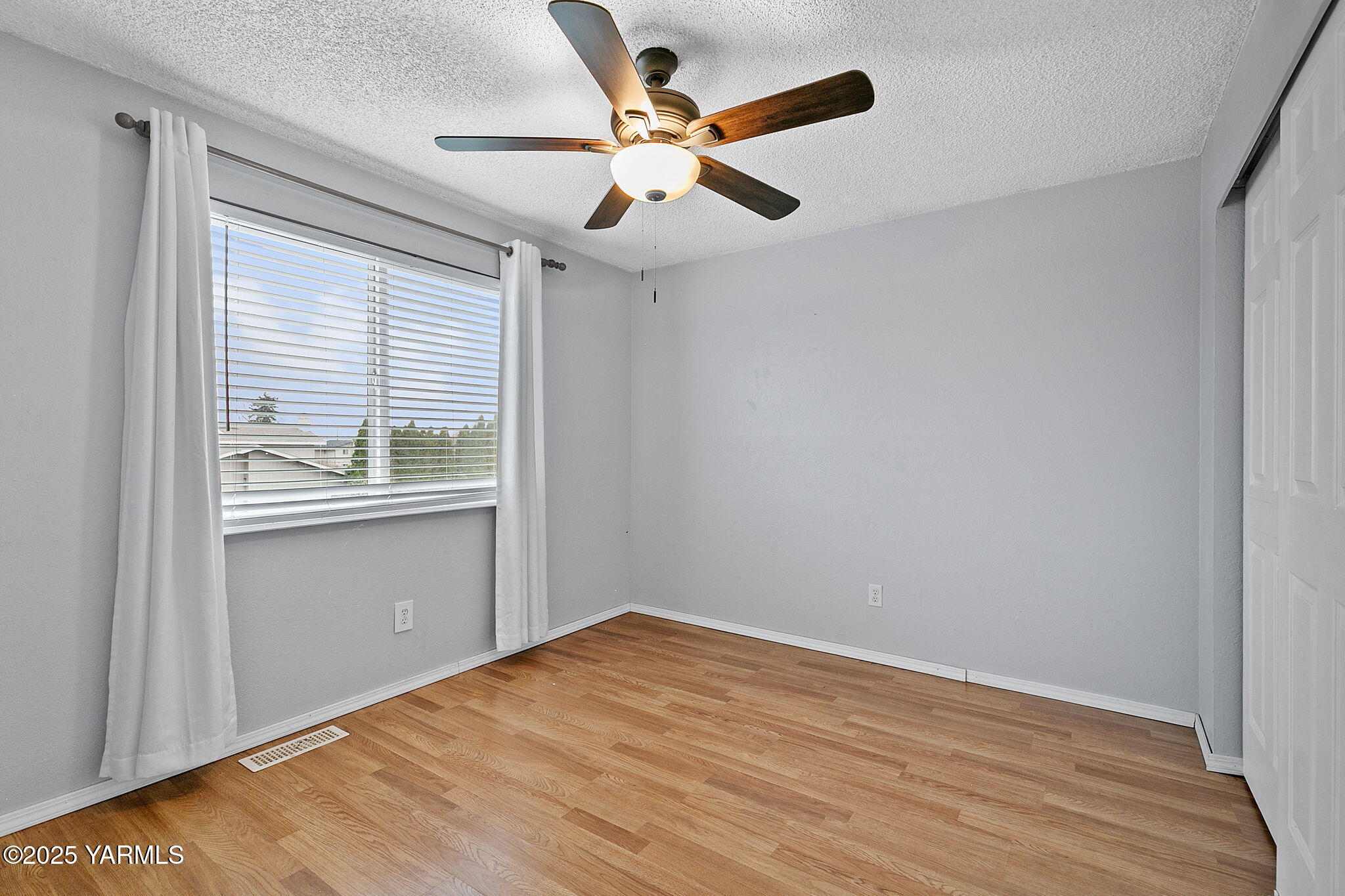 1106 South 33rd Avenue Yakima, WA 98902 - Photo 12 of 23 an empty room with wooden floor chandelier fan and windows