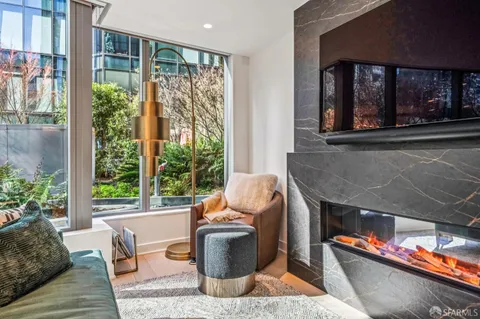 a living room with stainless steel appliances furniture and a kitchen view