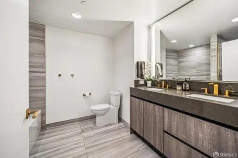 a view of a hallway with wooden floor and a bathroom