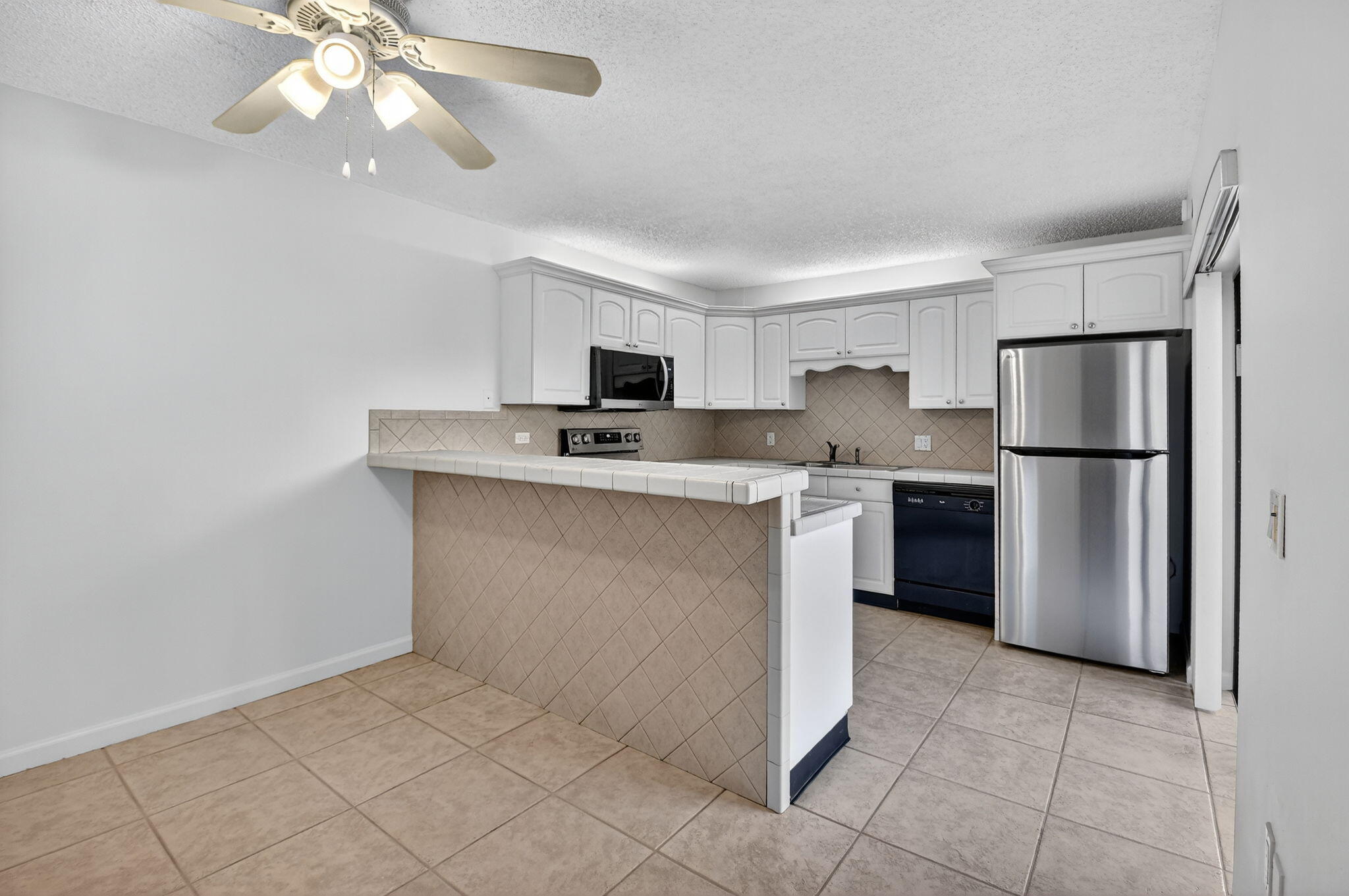 2907 Southwest 22nd Circle, Unit 39D Delray Beach, FL 33445 - Photo 6 of 57 a kitchen with stainless steel appliances a refrigerator sink and microwave