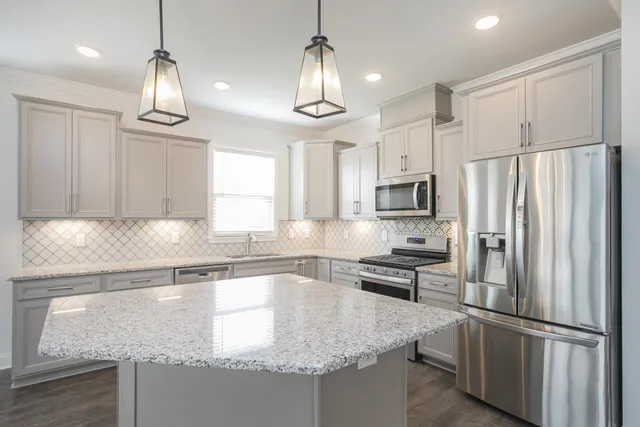 a kitchen with granite countertop a refrigerator a sink and wooden cabinets