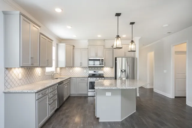 a kitchen with stainless steel appliances granite countertop a sink a stove and a refrigerator