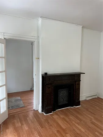 a view of an empty room with wooden floor and a fireplace