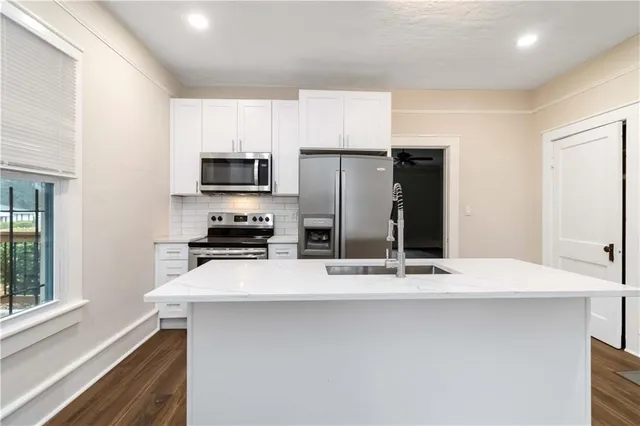 a kitchen with granite countertop a refrigerator and a stove top oven
