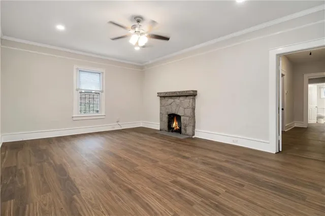 an empty room with wooden floor a fireplace and windows