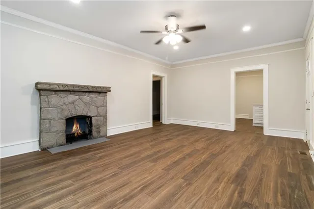 a view of an empty room with wooden floor fireplace and a window